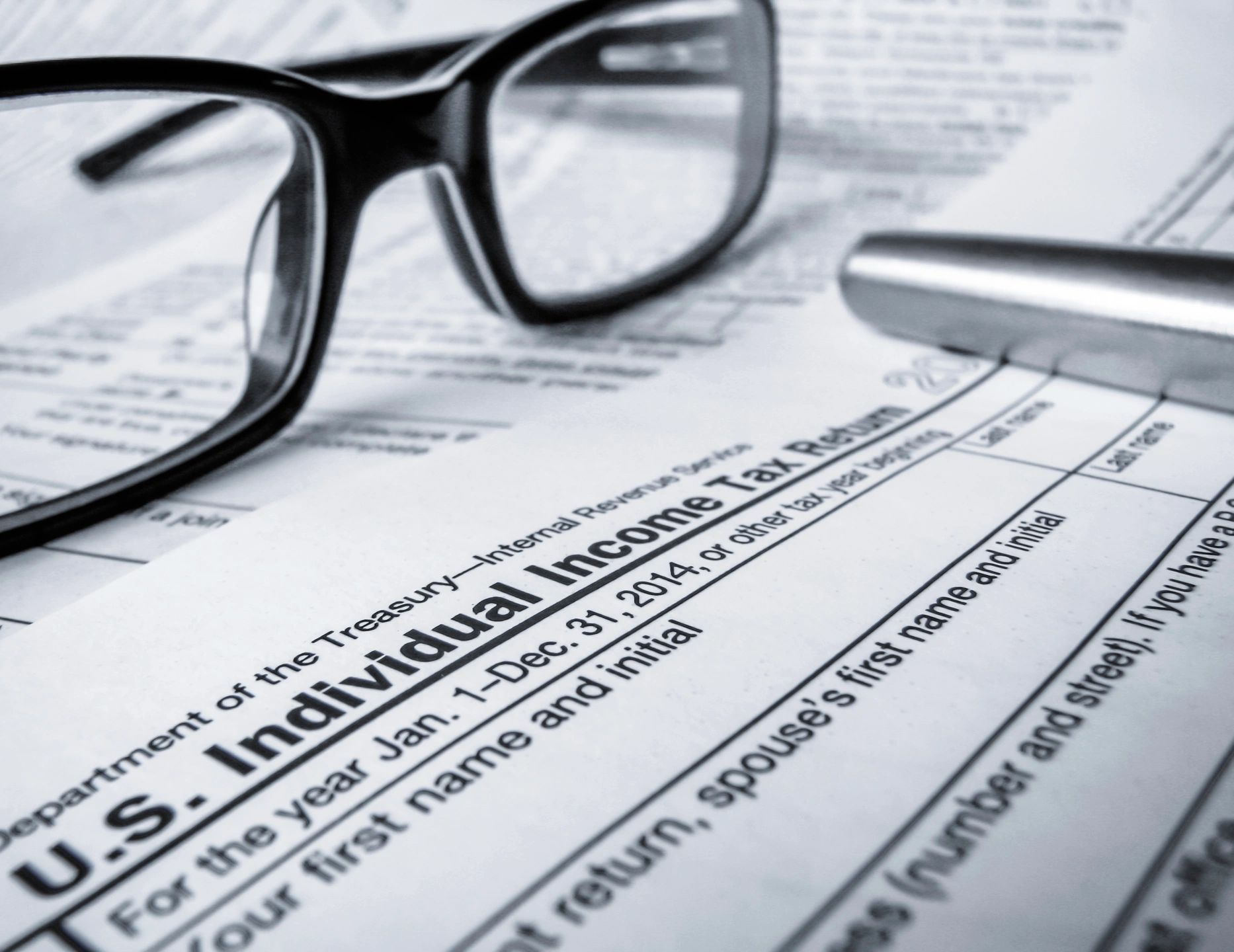 A pair of glasses sitting on top of some tax forms.