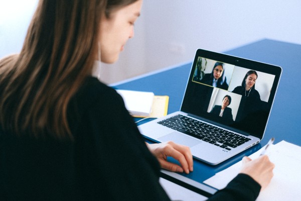 A woman is on her laptop and has three people in the background.