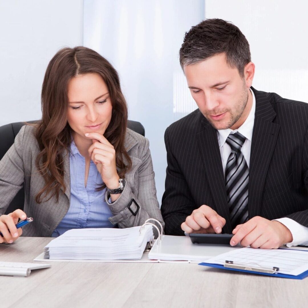 Two people sitting at a table looking at papers.